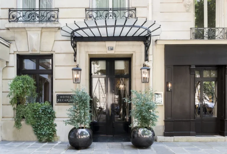 Entrance of Hôtel Récamier in Saint-Germain-des-Prés, Paris, with elegant stone façade, black doors and potted greenery.
