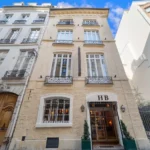 Exterior of Hôtel de la Bretonnerie in Le Marais, Paris, with classic cream stone façade and wrought-iron balconies.