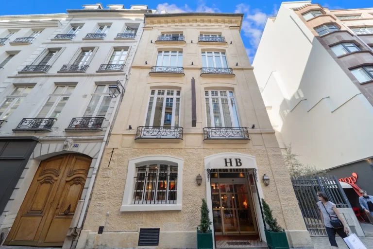 Exterior of Hôtel de la Bretonnerie in Le Marais, Paris, with classic cream stone façade and wrought-iron balconies.