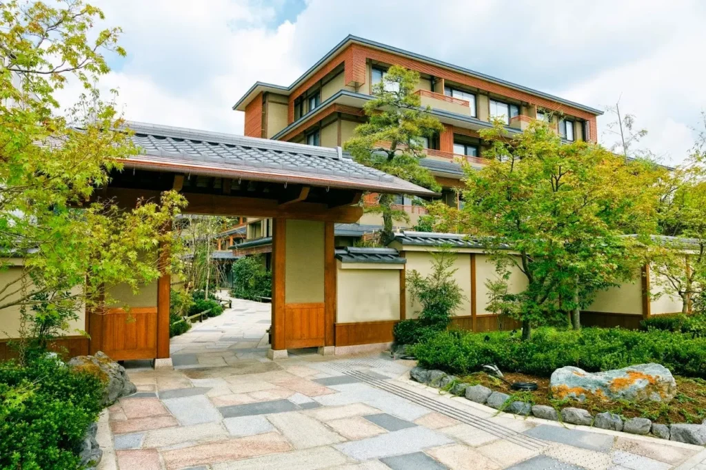 Traditional Japanese-style entrance and landscaped gardens at Kadensho Arashiyama Onsen in Kyoto, featuring wooden architecture and serene surroundings.