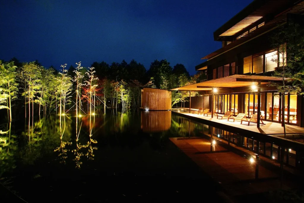 Night view of Kinnotake Sengokuhara in Hakone, featuring contemporary Japanese architecture, illuminated bamboo gardens, and a reflective water feature.