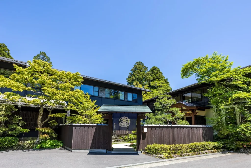 Exterior view of Matsuzakaya Honten ryokan in Hakone, featuring traditional Japanese architecture, wooden gates, landscaped gardens, and a peaceful mountain setting.