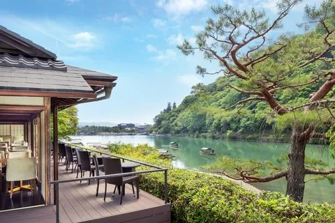 Riverside terrace dining area at Suiran, a Luxury Collection Hotel Kyoto, overlooking the tranquil Katsura River and surrounding Arashiyama greenery.