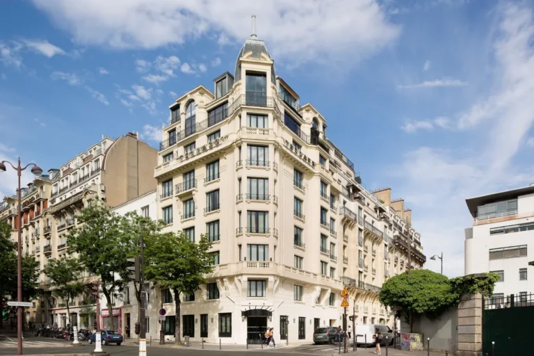 Exterior of Terrass Hôtel in Montmartre, Paris, featuring its elegant historic corner façade under a blue sky.