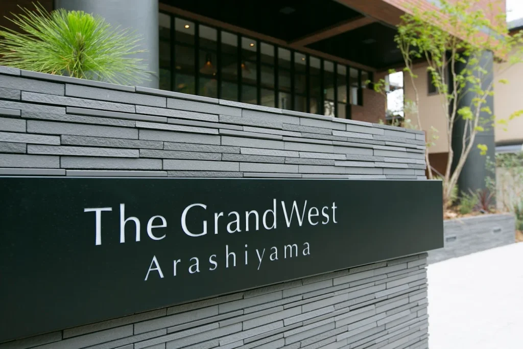 Entrance sign for The GrandWest Arashiyama hotel in Kyoto, featuring modern architecture, landscaped greenery, and a contemporary exterior design.