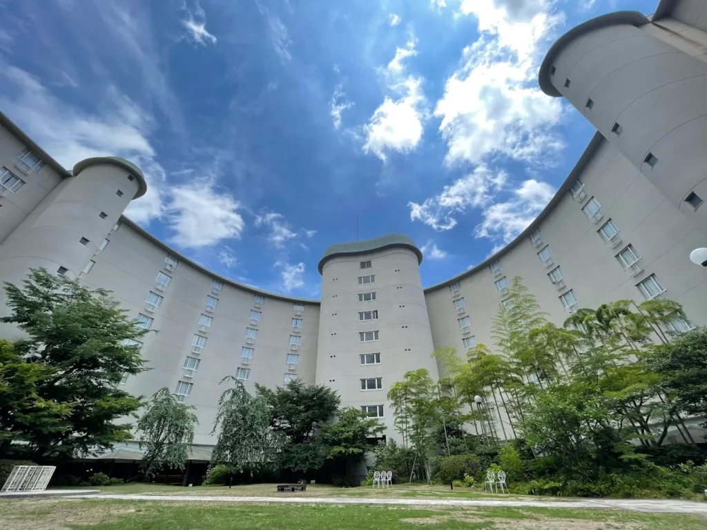 The Prince Kyoto Takaragaike hotel exterior surrounded by landscaped gardens under a bright blue sky in northern Kyoto, Japan