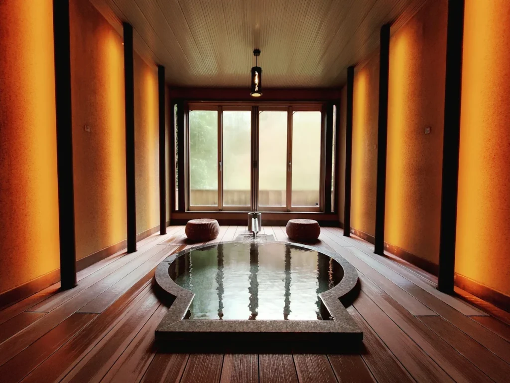 Private indoor onsen bath at Yama No Chaya ryokan in Hakone, featuring warm ambient lighting, wooden flooring, and a tranquil traditional Japanese design.