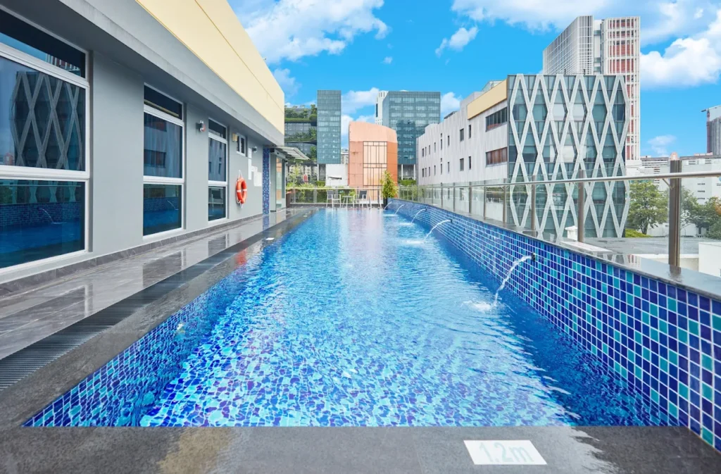 Rooftop swimming pool at ibis budget Singapore Clarke Quay with blue mosaic tiles, modern city buildings, and skyline views in the background.