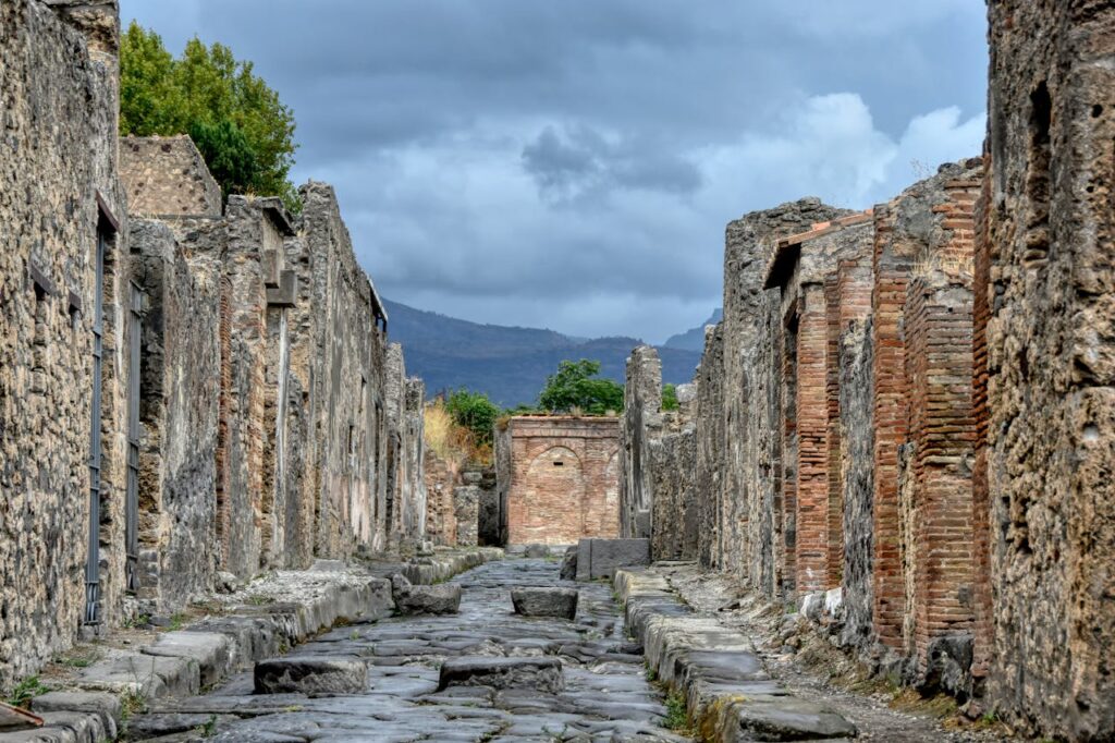 Ancient stone street lined with preserved buildings and ruins in Pompeii, showcasing the city's remarkably intact Roman architecture.