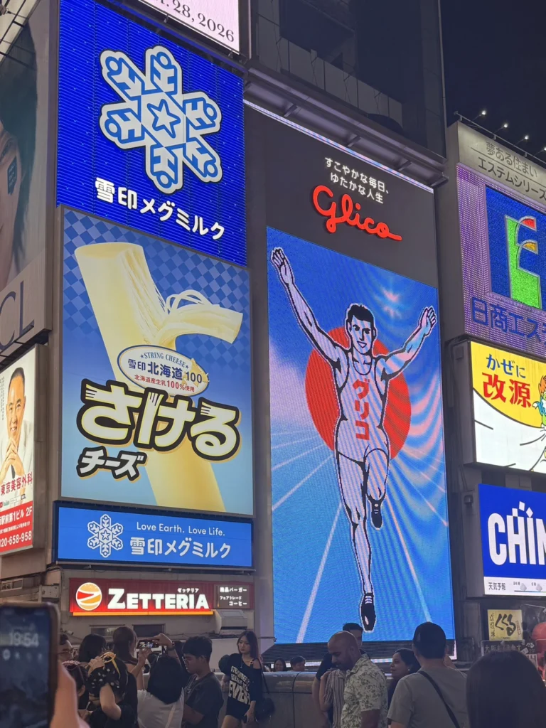 7-Day Osaka, Kyoto and Kobe Itinerary: Food, Shopping and Summer Sights 16 Glico Running Man sign illuminated above a crowd in Dotonbori, Osaka, at night.