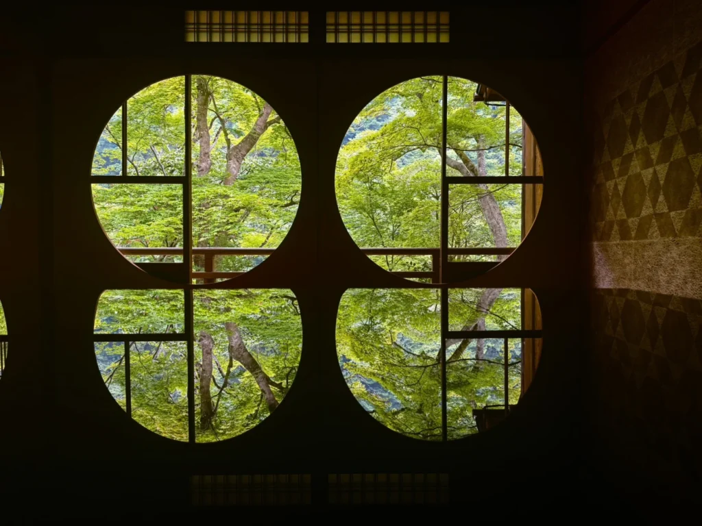 Circular windows reflected on the polished table inside Arashiyama Yusai-tei