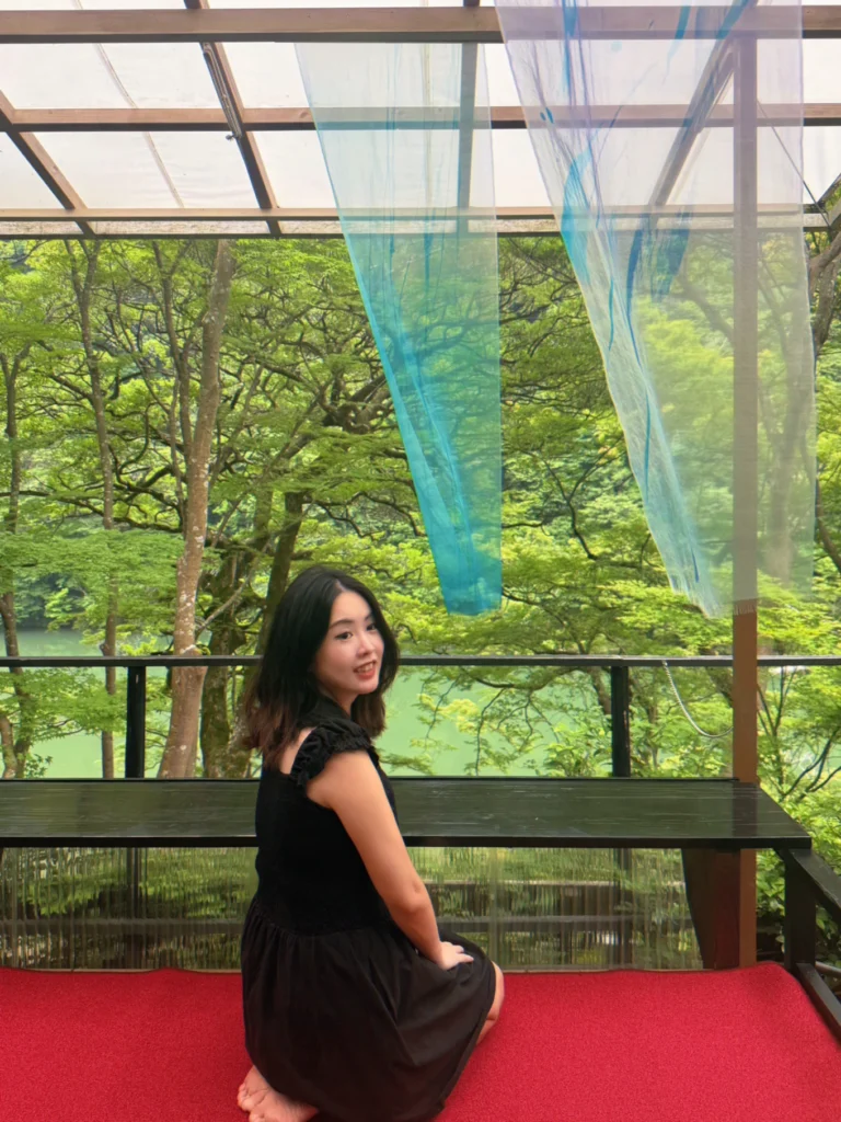 Visitor sitting beneath flowing blue silk installations overlooking the Katsura River