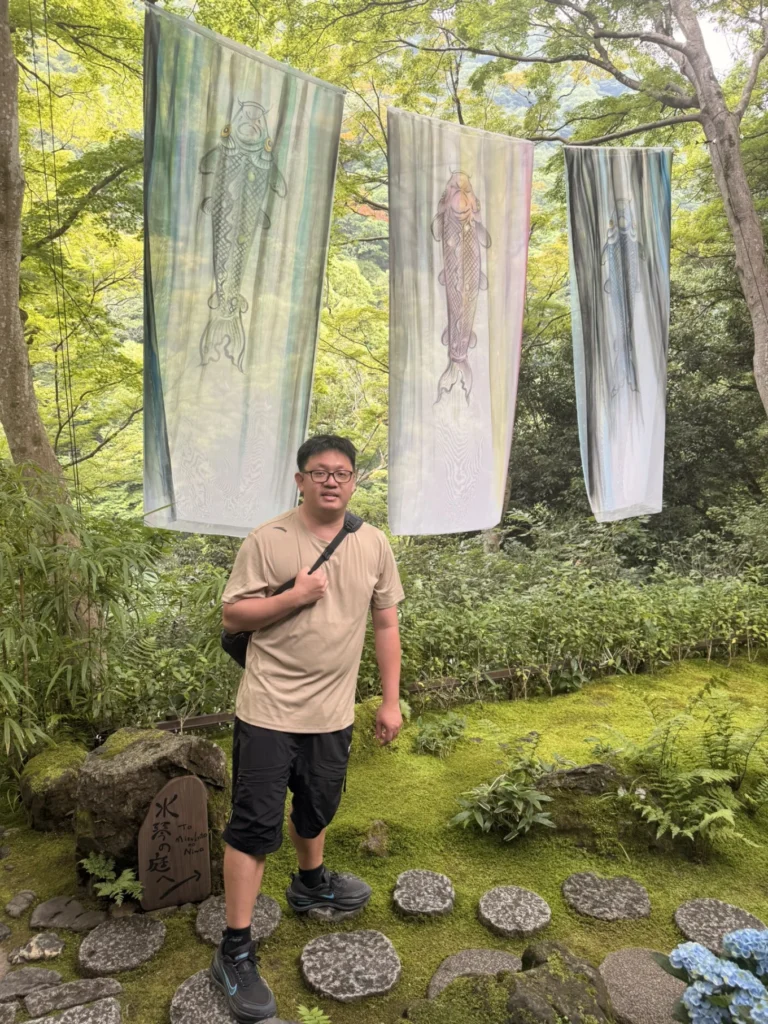 Visitor standing beneath silk art installation at Arashiyama Yusai-tei in Kyoto
