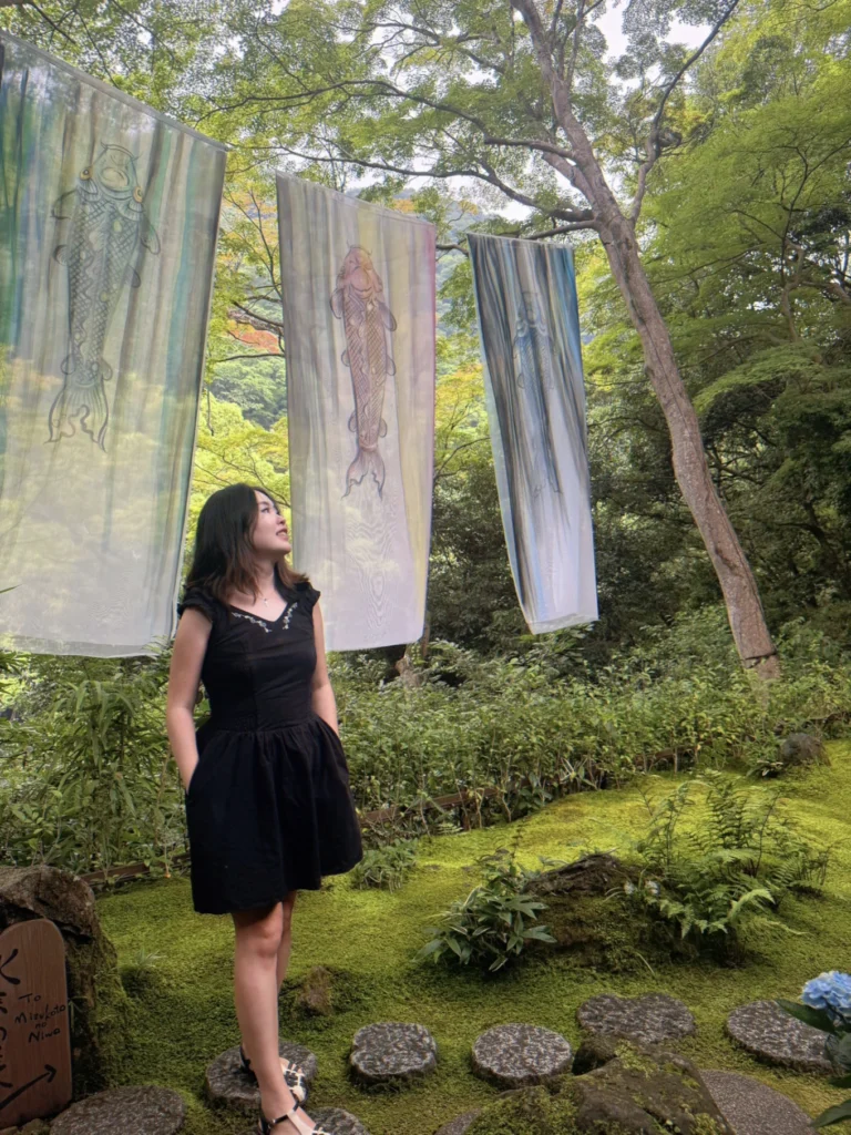 Visitor admiring colourful silk artwork in the tranquil garden of Arashiyama Yusai-tei