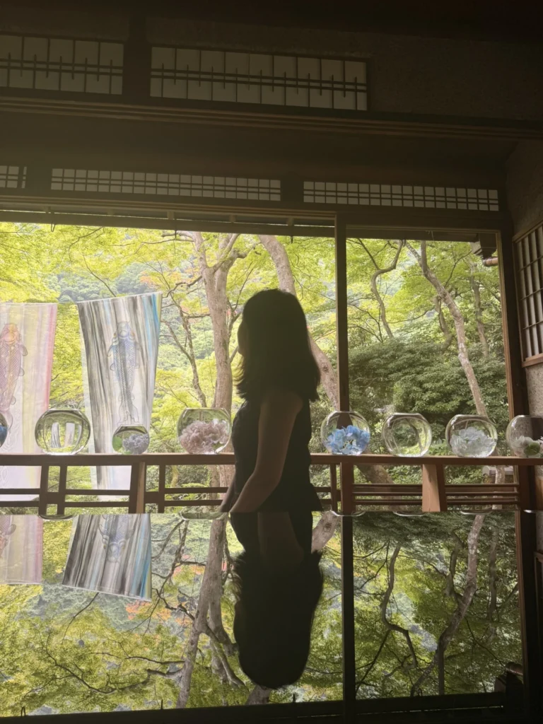 Reflection photography inside Arashiyama Yusai-tei with a visitor overlooking the garden