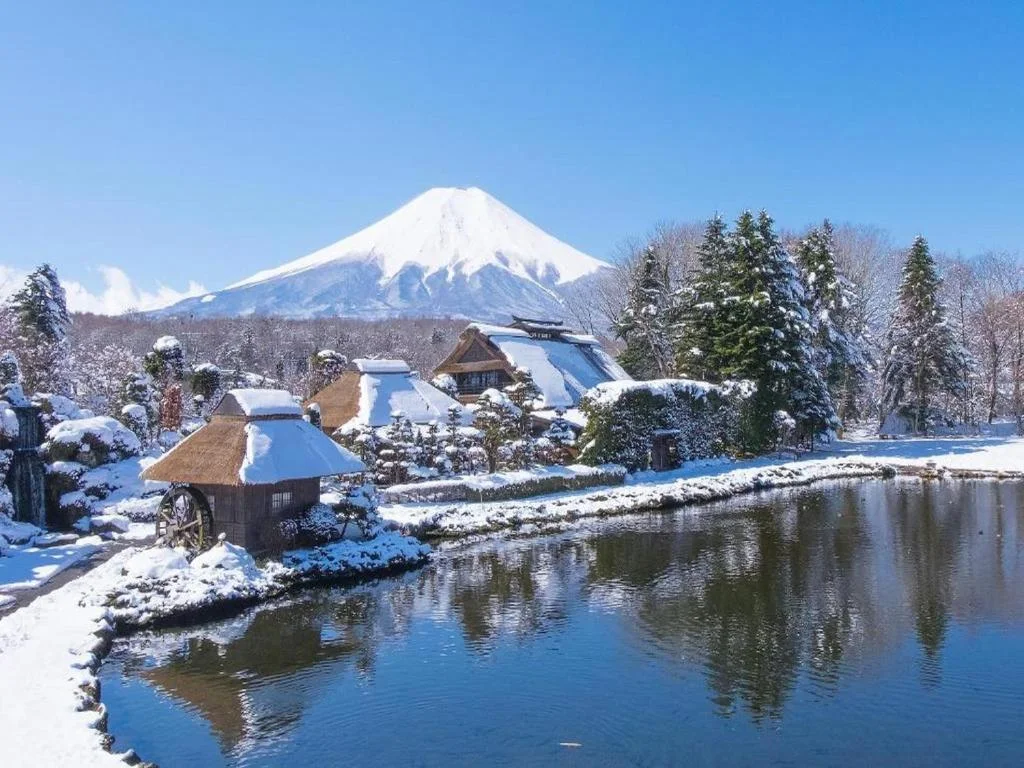 Snow-covered traditional village near HOTEL MYSTAYS Fuji Onsen Resort with Mount Fuji rising in the background on a clear winter day.