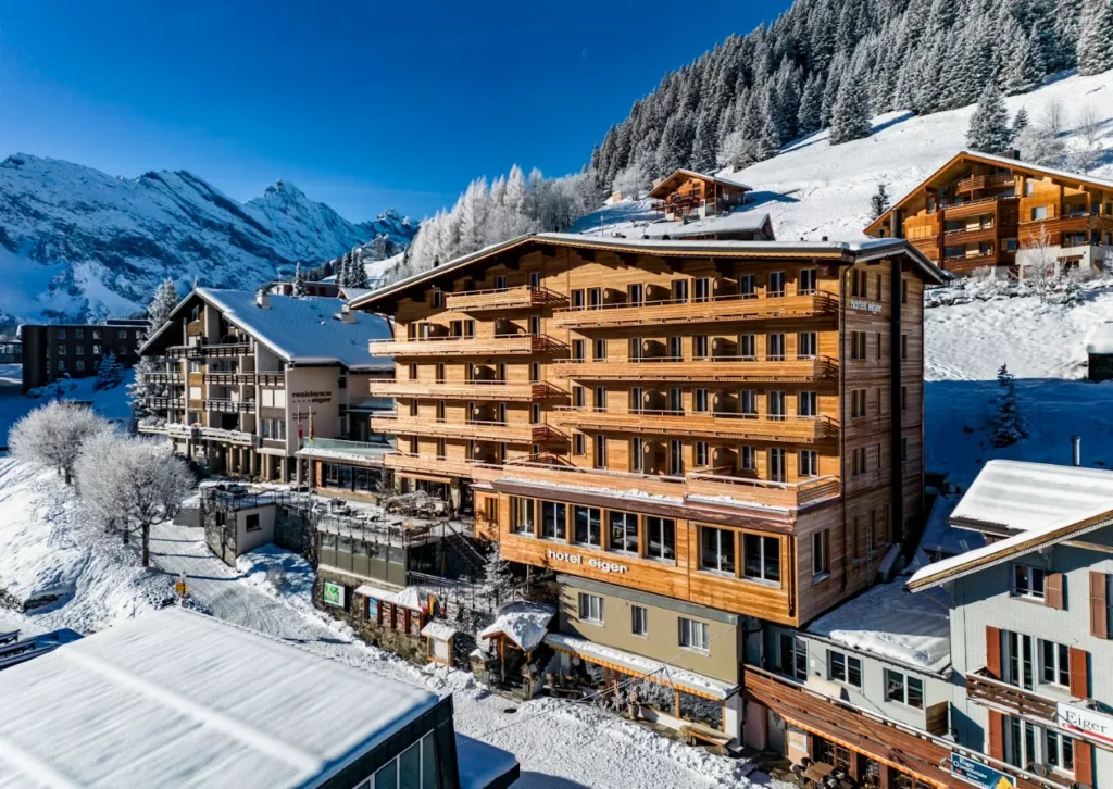 Exterior of Hotel Eiger Mürren, a traditional alpine hotel in the car-free village of Mürren, surrounded by snow-covered mountains in the Swiss Alps.