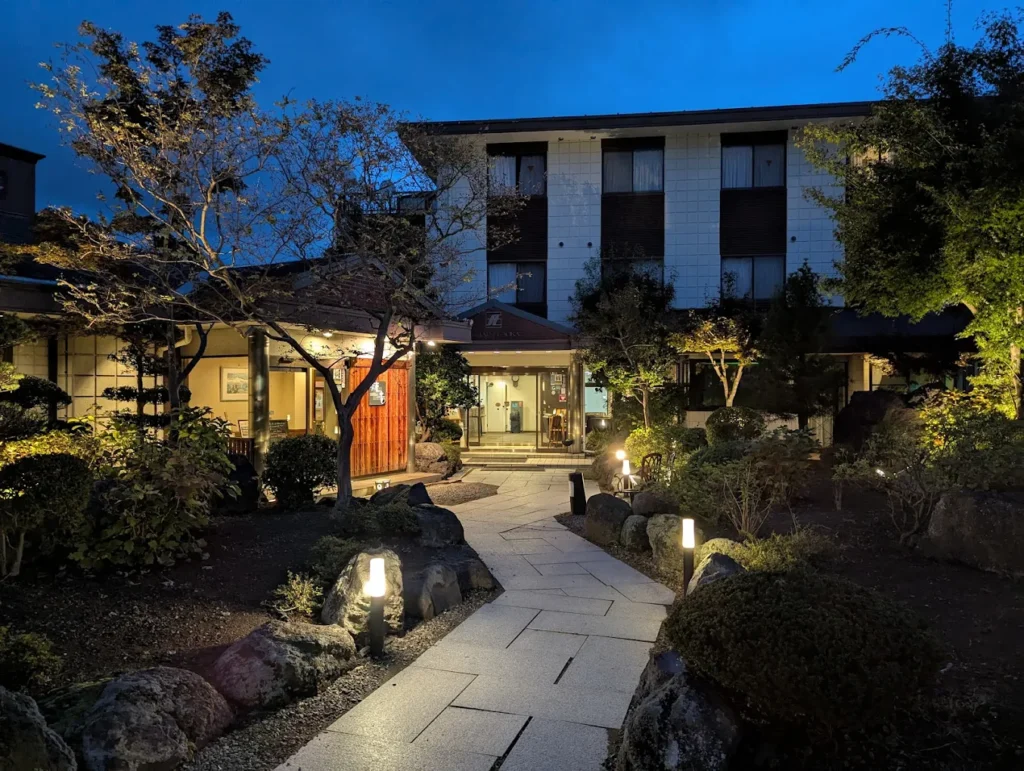 Evening view of Hotel Fuji Tatsugaoka in Fujiyoshida, Japan, featuring a peaceful Japanese garden and traditional-style entrance near Mount Fuji Station.
