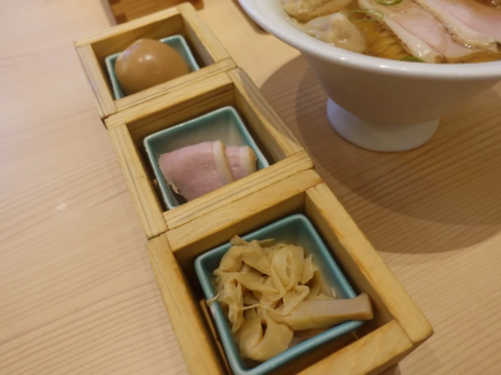 Premium toppings served in wooden boxes with seasoned egg, duck slices and bamboo shoots at Ramen Kamo to Negi Osaka Umeda