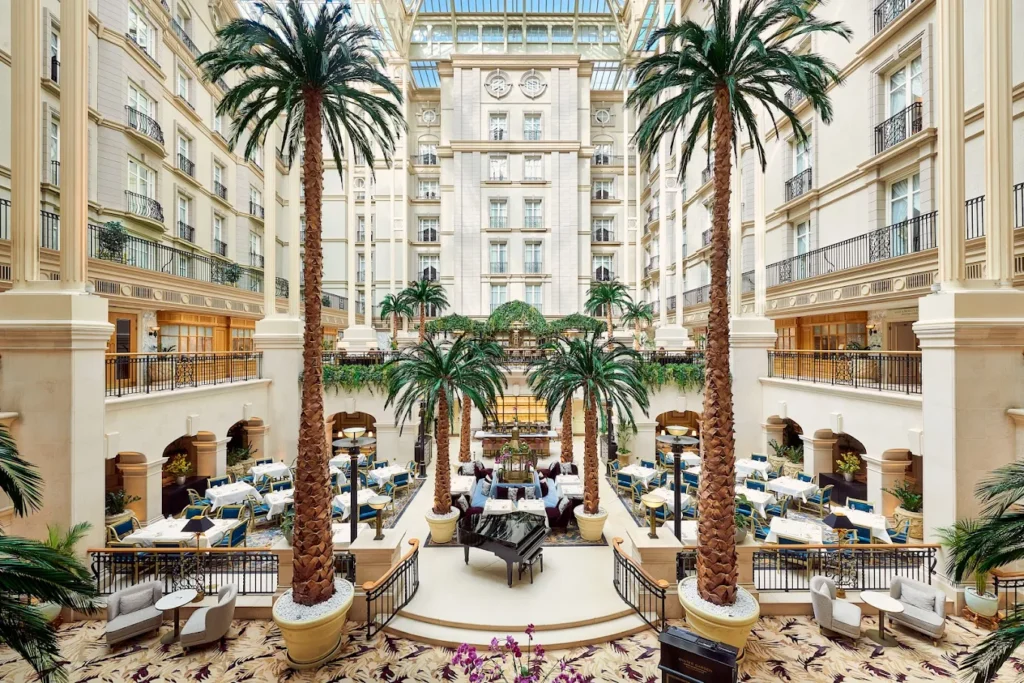 10 Best Muslim-Friendly Hotels (Halal) in London 6 The elegant glass-roofed Winter Garden atrium inside The Landmark London, featuring towering palm trees, luxury dining areas, and classic Victorian architecture.