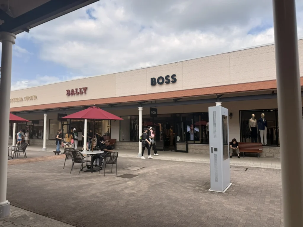 7-Day Osaka, Kyoto and Kobe Itinerary: Food, Shopping and Summer Sights 12 BOSS and Bally storefronts at Kobe-Sanda Premium Outlets with outdoor seating and shoppers.