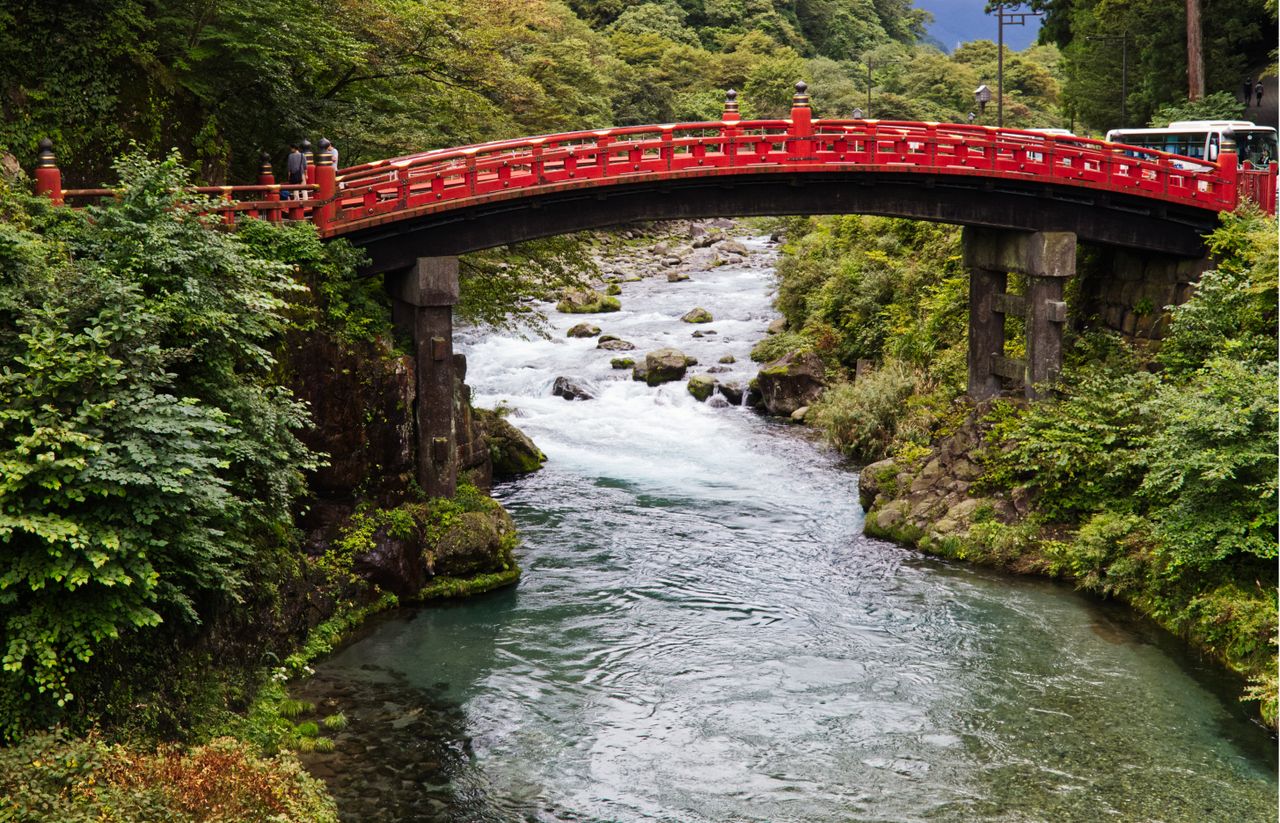 Shinkyo Bridge in Nikko spanning the Daiya River, surrounded by lush green forests, one of Japan's most famous historic landmarks near Toshogu Shrine.