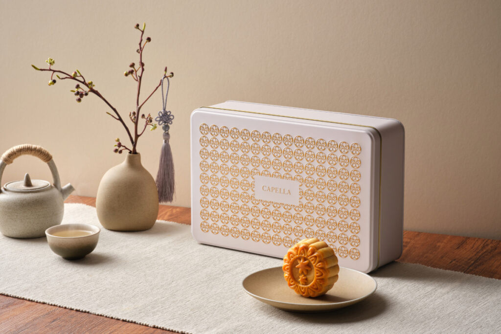 Capella Singapore 2026 mooncake presented beside a white and gold luxury gift tin with tea set