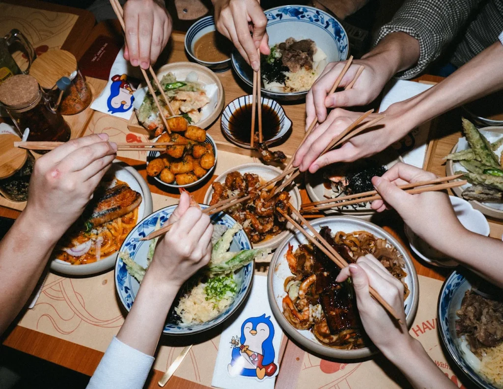 Lentor Modern Food Guide: 17 Best Places To Eat Near Lentor MRT 9 Diners sharing assorted udon, tempura and Japanese side dishes at UMAI in Lentor Modern.