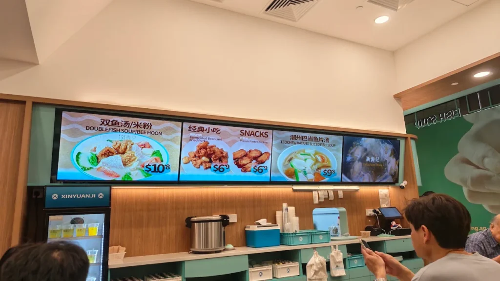 Lentor Modern Food Guide: 17 Best Places To Eat Near Lentor MRT 15 Xin Yuan Ji fish soup counter at Lentor Modern, with digital menu boards displaying sliced fish soup, bee hoon and side dishes.