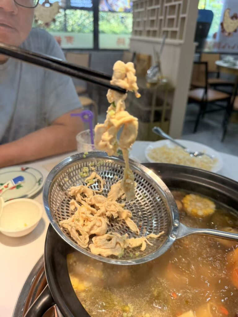 Chao Baba Freshly Cut Chicken Pot Review at SAFRA Punggol 11 Cooked chicken slices being lifted from the fig chicken soup at Chao Baba SAFRA Punggol.